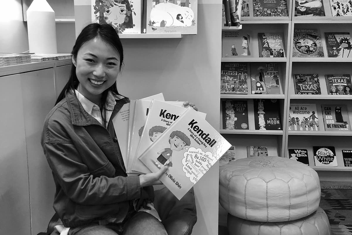 Liv Shin holding up a copy of her children's book, Kendall: A Story of a Young Boy with Autism